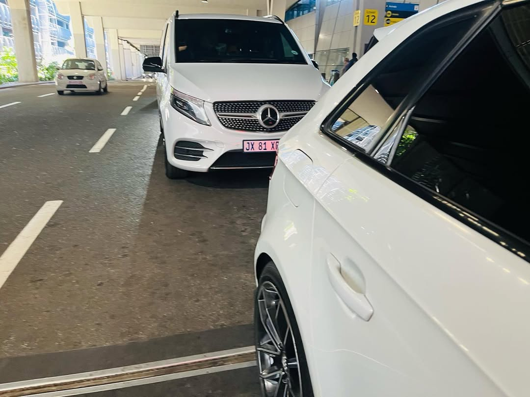 White V-Class and sedan at airport arrivals