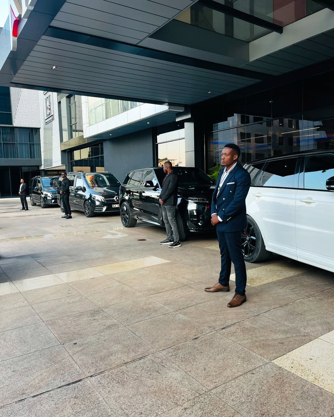 Chauffeurs standing with a lineup of vans and SUVs at a hotel entrance