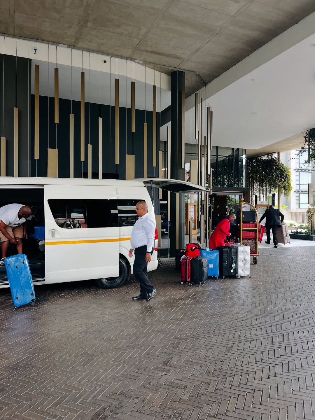Group shuttle loading luggage at a hotel entrance